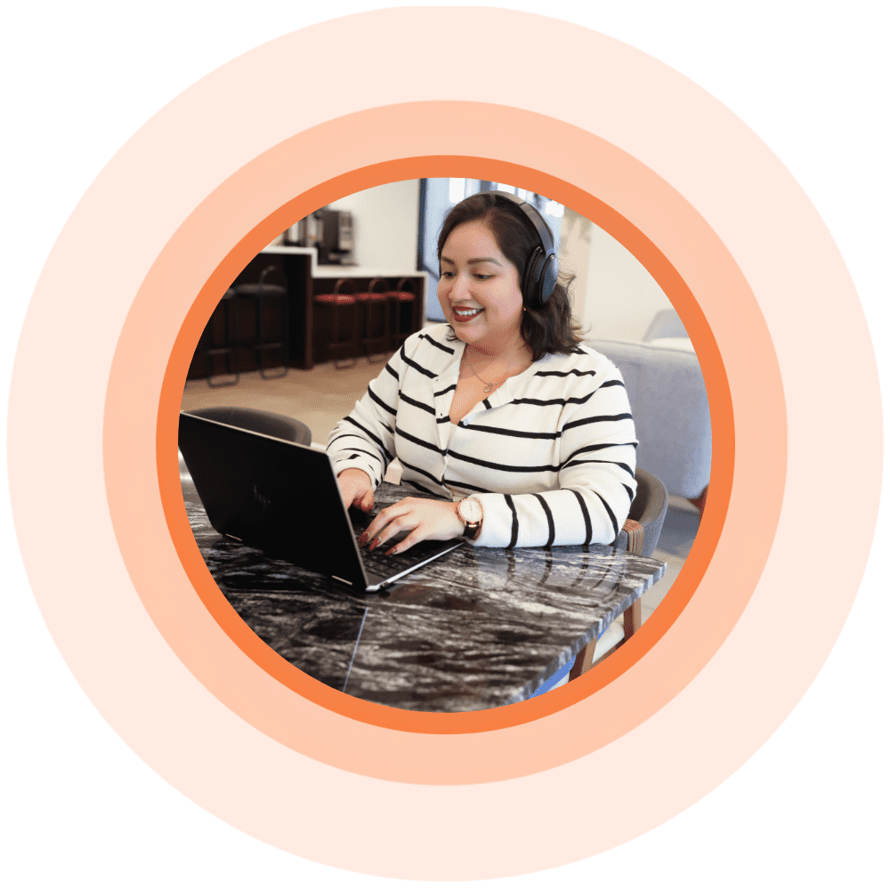 Women sitting at desk, wearing headphones and typing on laptop